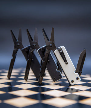 Set of multi-tool knives on a checkered surface with a blurred background