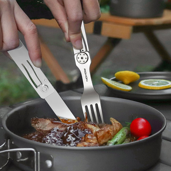 Person using a set of silver utensils to eat food from a pan with vegetables.
