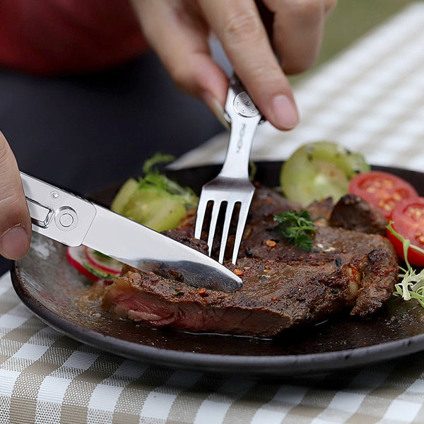Steak being cut with a knife and fork on a checkered tablecloth