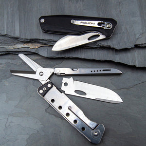 Multitool with knife, scissors, and other tools on a dark stone surface