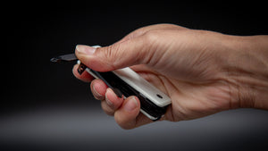 Hand holding a ks2e Noir Blanc multi-tool with a black and white case against a dark background
