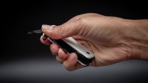 Hand holding a ks2e Noir Blanc multi-tool with a black and white case against a dark background