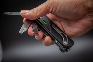 Hand holding a multi-tool with various components on a dark background