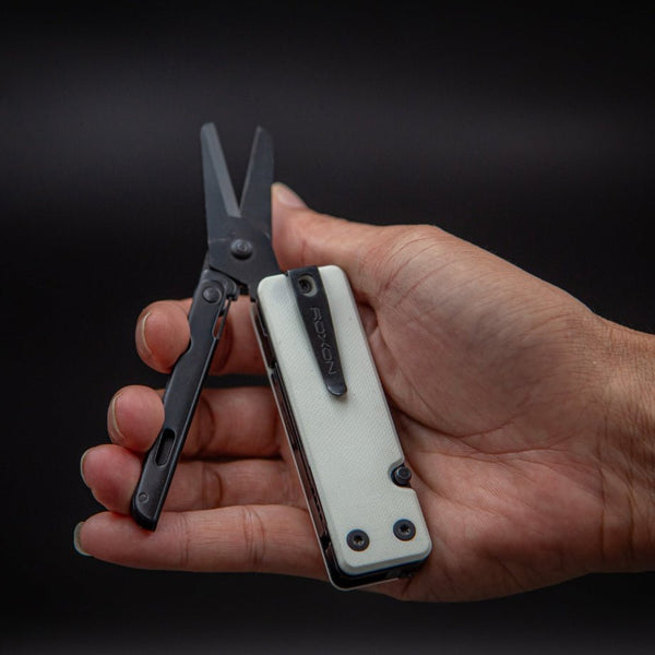 Hand holding a multi-tool with scissors on a black background