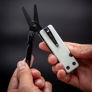 Multitool with scissors held by a person against a dark background