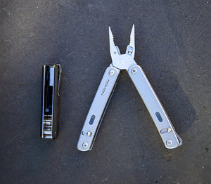 Roxon multitool with pliers fully extended displayed next to a compact modular multitool with visible bit driver storage, both placed on a dark surface.