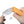 Folding knife with orange handle held by a hand on a white background