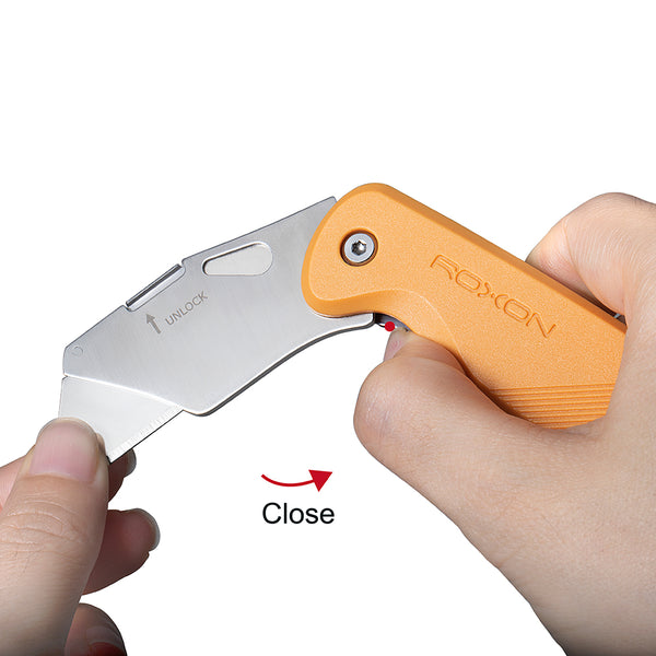 Folding knife with orange handle held by a hand on a white background