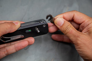 Person holding a multi-tool with various components on a gray background