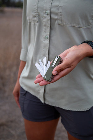 Person holding a multi-tool in their hand with a natural background