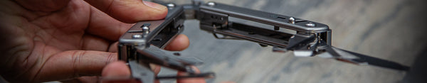 Metal folding tool held in a hand with a blurred background