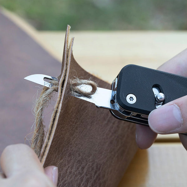 Person using a leather edge tool on a piece of leather with a blurred background