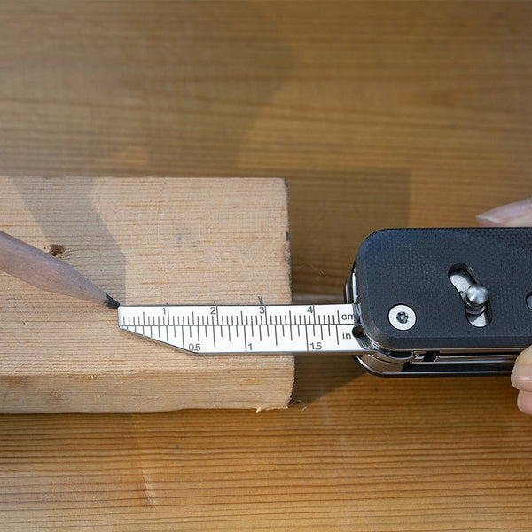 Multitool with ruler and pencil on a wooden surface