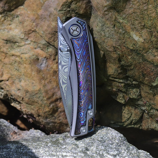 Folding knife with a decorative blade on a rock background