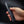 Hand holding a black folding knife against a dark background